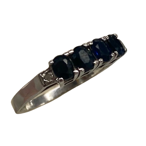Ladies 9ct White Gold 6 Stone Sapphire & Diamond Ring. 4 Oval Sapphires, 4 Claw Set. With 2 Square Grain Set Diamonds In Swept Up Shoulders. TDW 1.15ct. Size P/8 . With Valuation Certificate – (NG 73254)