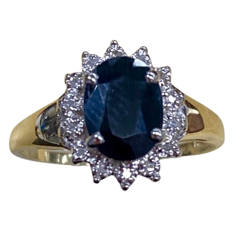 Ladies 9ct Yellow Gold 15 Stone Diamond & Sapphire Ring. Oval Sapphire In Rhodium 4 Claw Setting, Surrounded by 14 Single Cut Diamonds Illusion Bead Set in Rhodium Plated Basket, In Swept Up Shoulders. TDW 0.07ct. Size M/6.5, With Valuation Certificate – (NG 1307520)