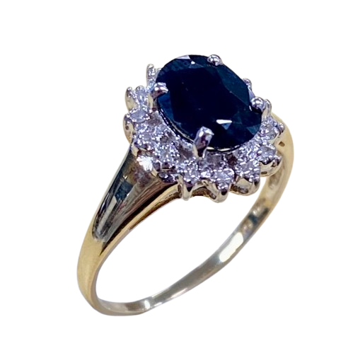 Ladies 9ct Yellow Gold 15 Stone Diamond & Sapphire Ring. Oval Sapphire In Rhodium 4 Claw Setting, Surrounded by 14 Single Cut Diamonds Illusion Bead Set in Rhodium Plated Basket, In Swept Up Shoulders. TDW 0.07ct. Size M/6.5, With Valuation Certificate – (NG 1307520)