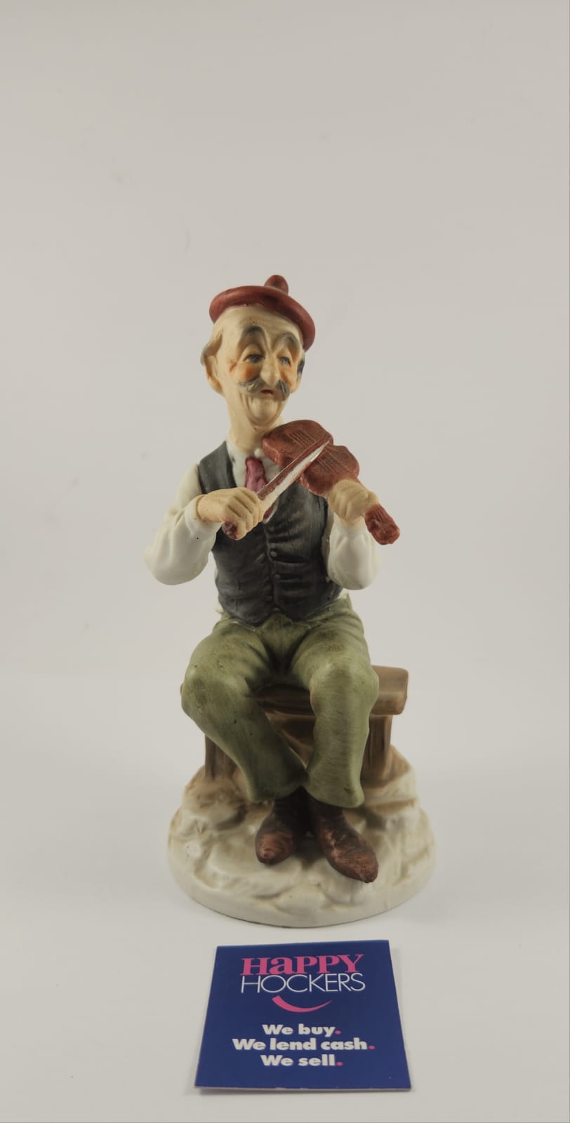 CERAMIC FIGURINE OF MAN SITTING ON BENCH PLAYING VIOLIN